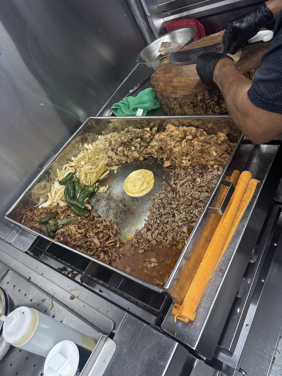 The comal inside the truck loaded with meats, onions, and tortillas