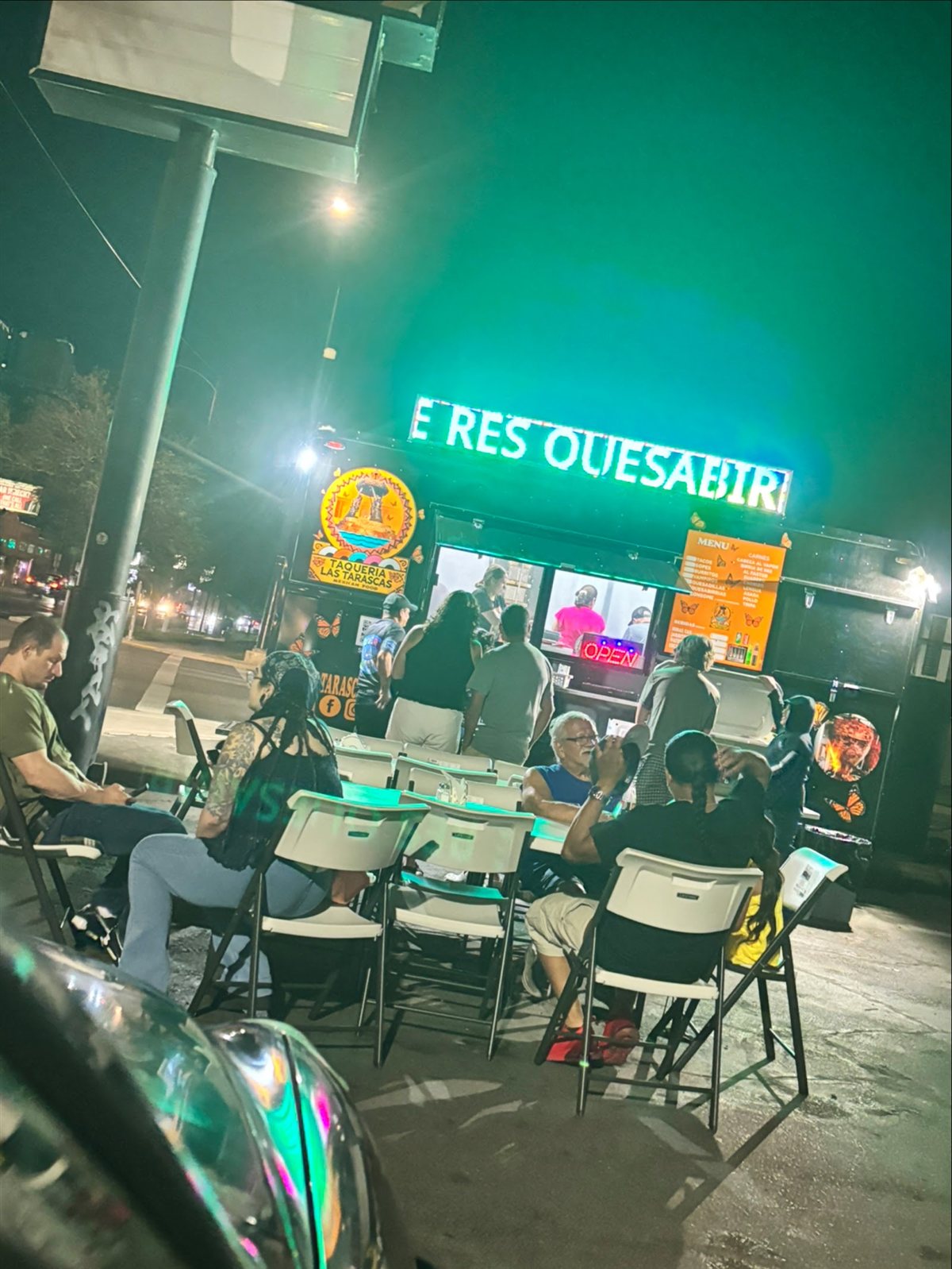 The Las Tarascas food truck at night with its neon quesabirria sign and a full crowd